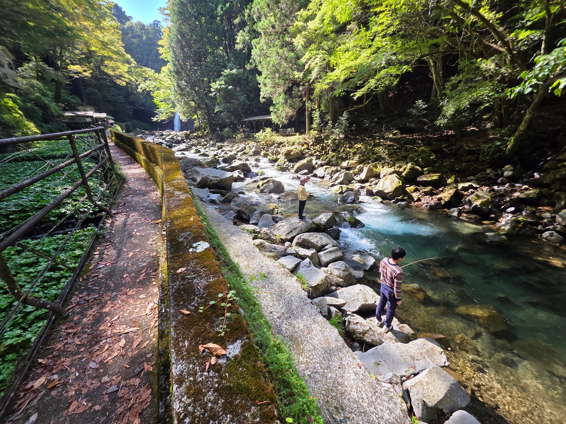 浄蓮の滝の下流の澄んだ川で釣りを楽しむ人たち