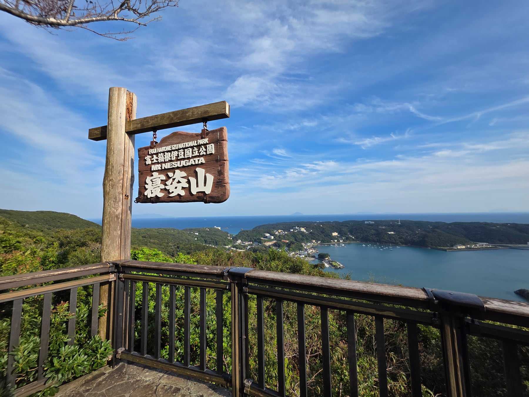 寝姿山の木製看板と下田湾の眺め